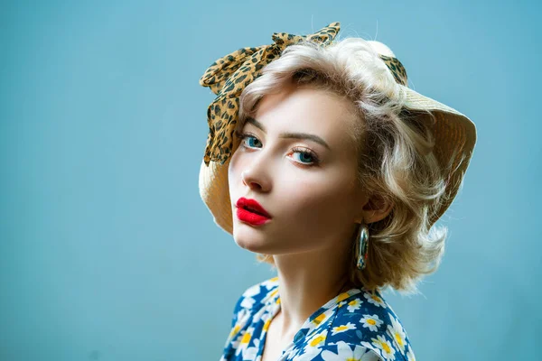 Beauty pin up girl on blue wall. Young woman dressed in pin-up style. Blond model in retro hat posing on isolated grey background. — Stock Photo, Image