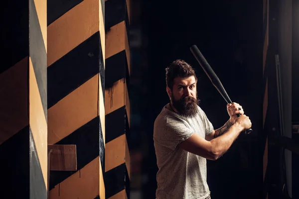Angry man in t-shirt. Ready to swing. Gangster with bat weapon. Bearded man hold baseball bat. Angry hooligan. Aggression or anger and violence concept. Threatening angry man with a beard.