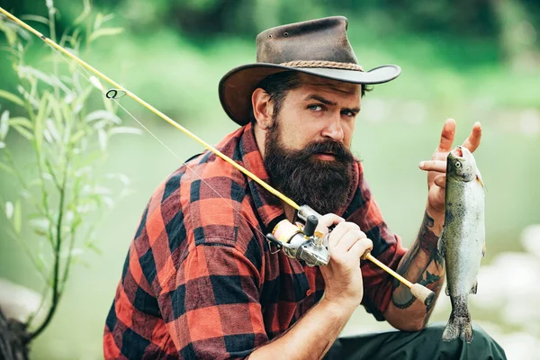 Porträt eines Mannes im Urlaub. Fischereihintergrund. Abenteuer Fliegenfischen. Mann im Hemd angelt mit Rute auf dem See. Wochenendzeit. Mann fischt einen Fisch. — Stockfoto