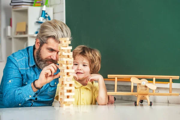 Playing Jenga. Pupils Education. Cute little preschool kid boy with teacher playing in a classroom. Learning and education concept.