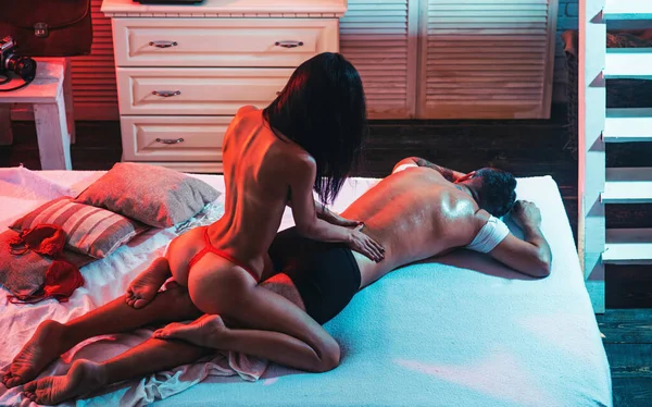 Szexi fiatal nő fehérneműben masszírozza a pasiját az ágyban. Szexi fiatal pár levetkőzve. Érzéki szexi pár. Gyönyörű női test izmos férfi. — Stock Fotó