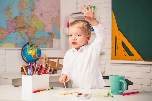 Glückliches, nettes, fleißiges Kind sitzt drinnen an einem Schreibtisch. Zurück zur Schule. Hausaufgabenbetreuung. Talentiertes Kind. Kind macht sich bereit für die Schule. — Stockfoto