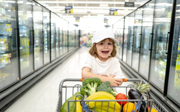 幼児男の子子供とともにショッピングバッグでスーパーマーケット. — ストック写真
