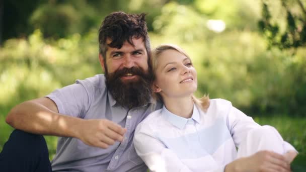 Una pareja cariñosa abrazándose en el parque. Pareja primavera verano. Chica feliz y barbudo pasar tiempo sentado en el parque en la hierba. Concepto de relajación en el parque . — Vídeos de Stock