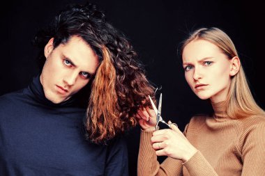 Uzun dalgalı saçlı ve tatlı kız arkadaşı olan yakışıklı bir adam. Makaslı bir kadın harika bir erkek tıraşı olacak. Erkek saç stili, sağlık ve moda. Memnun olmayan müşteri bakışı..