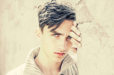 Ciddi bir yüz. Gri arka plandaki yakışıklı genç adam kameraya bakıyor..