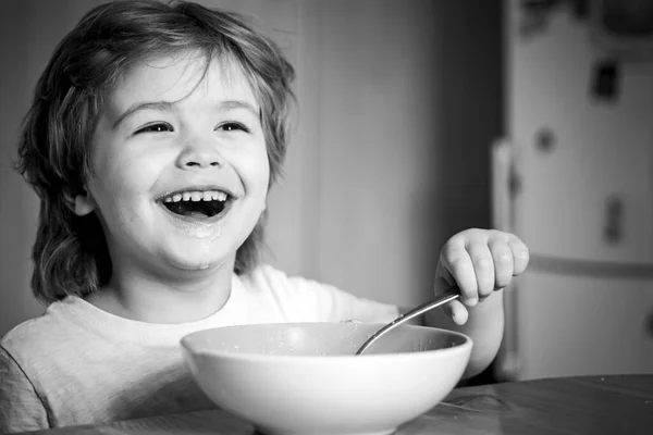 Kid eten. Kleine jongen met ontbijt in de keuken. Glimlachend gelukkig schattige baby eten fruit mash in de keuken. Hongerige kleine jongen eten. — Stockfoto