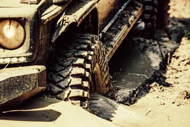 Alt manzaradan büyük off-road araba tekerine, şehir yolu ve dağ zemininde. Off-road aracı dağ yolunda gidiyor. Lastikler yarışa hazırlanıyor. Ralli yarışı.