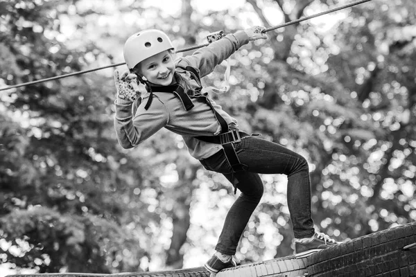 High ropes walk. Active children. Playground. Eco Resort Activities. Happy child boy calling while climbing high tree and ropes. Safe Climbing extreme sport with helmet.
