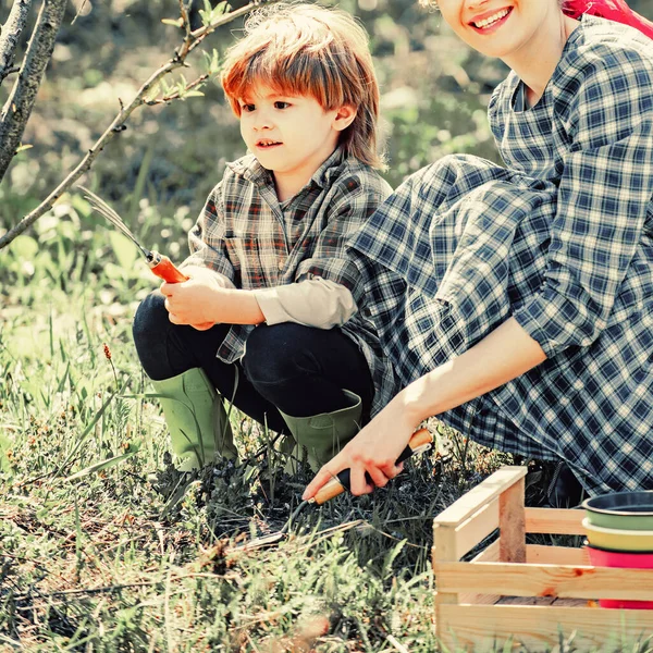 Mother and son farmers in the farm with countryside background. Eco farm. Happy family gardener carrying harvested in farm. Mother and son having fun with little shovel and plant in pot. — 스톡 사진