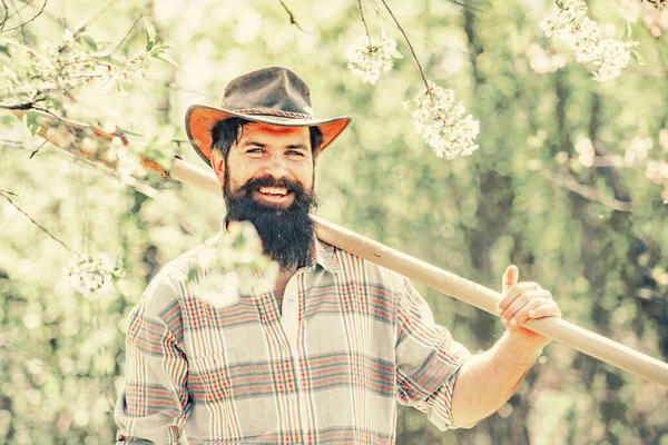 Mann arbeitet im Garten in der Nähe von Blumengarten. Gärtner arbeiten im Garten mit Gartengeräten und haben Spaß. — Stockfoto