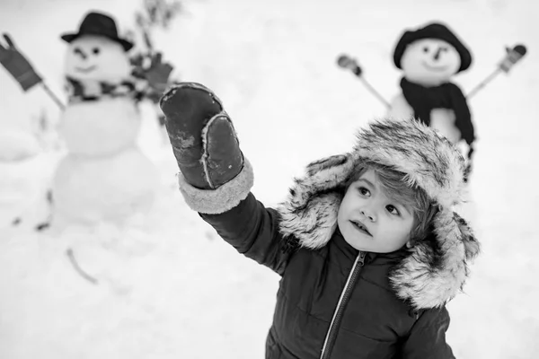 Child boy Having Fun in Winter Park. Winter clothes for kids. Happy winter time. Beauty child with snowman in frosty winter Park. — Stock Photo, Image