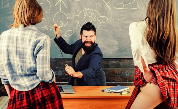 섹시 선생님은 섹시 한 여학생 두 명을 보고 있습니다. 에로틱 교육. 교육과 성의 상징이 칠판에 있습니다. 고등학교에서의 교육과 성 교육. — 스톡 사진