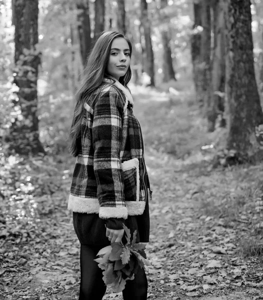 Autumn sale. Beautiful happy smiling girl with long hair wearing stylish jacket posing in autumn day. Autumn portrait smiling woman holds yellow maple leaves in park. — Stock Photo, Image