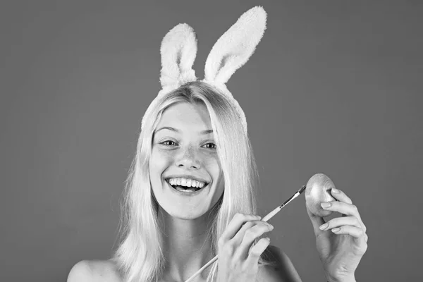 Mujer joven y feliz pintando huevos sobre un fondo rojo. Lindo conejito. Una joven atractiva con orejas de conejo. Feliz Pascua. . — Foto de Stock