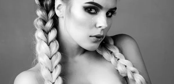 Ögonen blinkar. Headshot foto av elegant europeisk kvinnlig modell med färgglada makeup och flätor. Studio skott av het tjej tittar på kameran. — Stockfoto