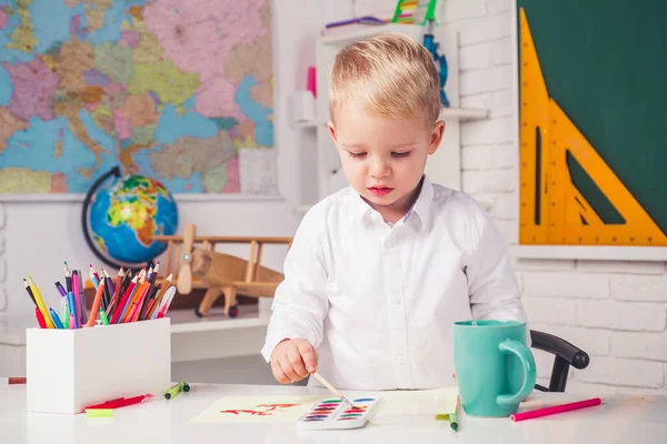 Gelukkige schoolkinderen bij de les. Hij maakt zich klaar voor school. Leuke leerling met grappig gezichtsonderwijs werk. Onderwijsproces. — Stockfoto