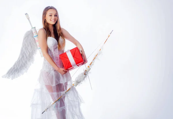 Cute little female cupid shoots a bow. Arrow of love. Little goddess with white wings alone on blue sky background. Teen angel. Cute teen girl. Angel children girl with white wings. Stock Image