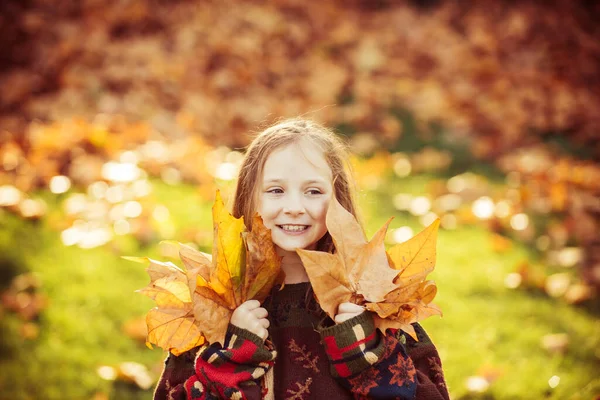 Ragazzina felice ride all'aperto. Giocare con le foglie. Luminose foglie gialle. Un ragazzino che gioca nel parco autunnale. Ragazzina carina nel parco autunnale. Il bambino gioca con foglie d'acero dorate. — Foto Stock