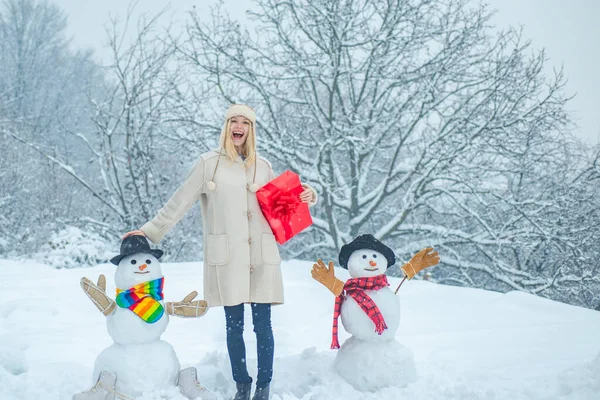 Zimní emoce. Zimní oblečení pro ženy. Šťastná dívka si hraje se sněhulákem na zasněžené zimní procházce. Zimní ráno. — Stock fotografie
