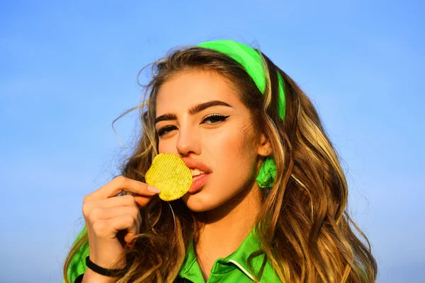 Retrato de mulher jovem, lábios bonitos, maquiagem brilhante segurando, comendo batata frita, batatas fritas, batatas fritas e posando sobre fundo azul. Comida pouco saudável. Mulher bonita comendo batatas fritas, close up . — Fotografia de Stock