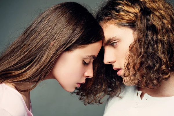 Couple looking at each other - close up sensual portrait. Man vs woman faces on gray background. Confrontation and competition. Couple face concept.