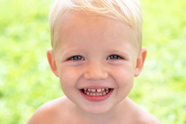 Joli visage d'enfant. Gros plan portrait d'un enfant garçon souriant heureux sur fond de nature verte. Journée de l'enfance. Les enfants sourient. Concept de bonheur des enfants. — Photo