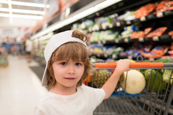 Smiling american kid with shopping trolley with in grocery store. Supermarket, Shopping with Child. — Stock Photo, Image