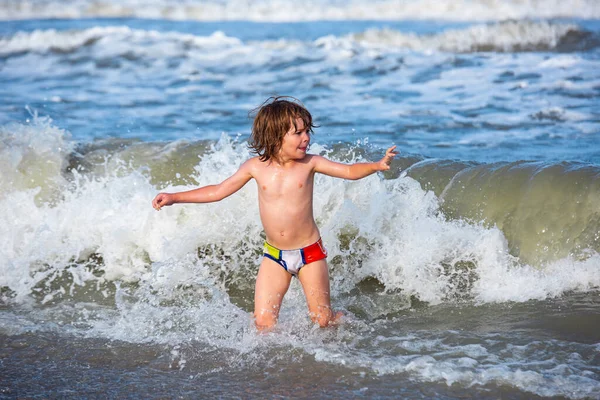 Mały chłopiec bawiący się na świeżym powietrzu skaczący do wody na letnie wakacje na tropikalnej wyspie plaży. Szczęśliwe dziecko bawiące się w morzu. — Zdjęcie stockowe