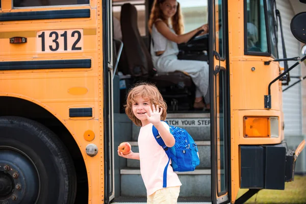 Школьник перед школьным автобусом с яблоком и сумкой . — стоковое фото