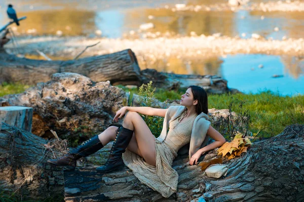 Portrait of a beautiful woman in a light dress. Vintage style photography of pretty girl in forest or park. Beautiful young woman in a park. Adult girl relaxed sitting on wood in an outdoor park. — Stock Photo, Image