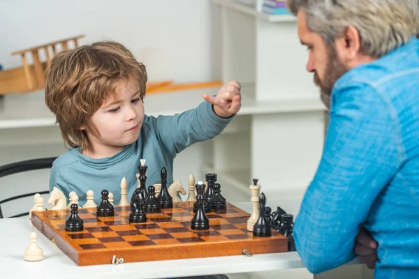 Vader met zoon die thuis schaak speelt. Terug naar school. Vader leert zijn zoon schaken.. — Stockfoto