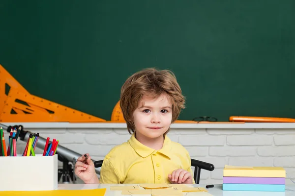 Gelukkig schattig ijverig kind zit binnen aan een bureau. Individuele begeleiding. — Stockfoto