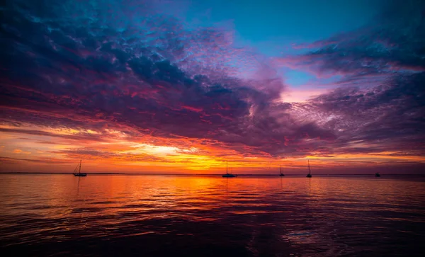 Bright sunset with large yellow sun under the sea surface. Beautiful tropical sunrise on the beach. — Stock Photo, Image