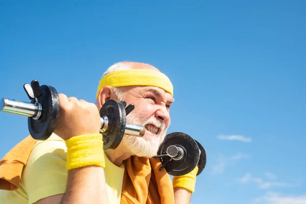 Senior sportman exercising with lifting dumbbell on blue sky background - close up portrait. 고립되고, 복사 공간. — 스톡 사진