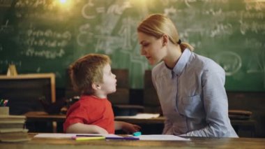 Evde eğitim. Mutlu anne ve gülümseyen oğul birlikte öğreniyor. Anne çocuğa ödevlerinde yardım ediyor. Anne ve küçük çocuk evde eğitim görüyor. Özel ders veren çocuklar..