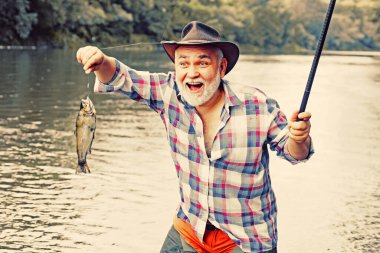 Balık yakalayan sakallı adam. Erkek hobisi. Suyun arka planında ormanın bir yansıması var. Emeklilik sadece bir başlangıç. İyi balık avları. Sadece bunu yap..