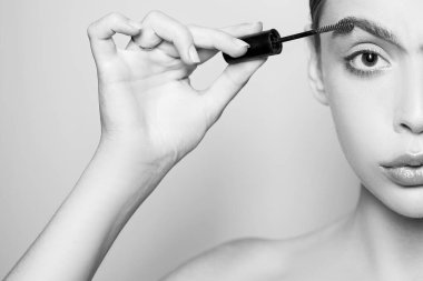 Genç ve güzel bir kadın doğal kaş makyajı yapıyor. Profesyonel çıplak makyajlı ve pürüzsüz sağlıklı ciltli bir kızın portresi. Güzel kız kaş makyajı için jel kullanıyor..