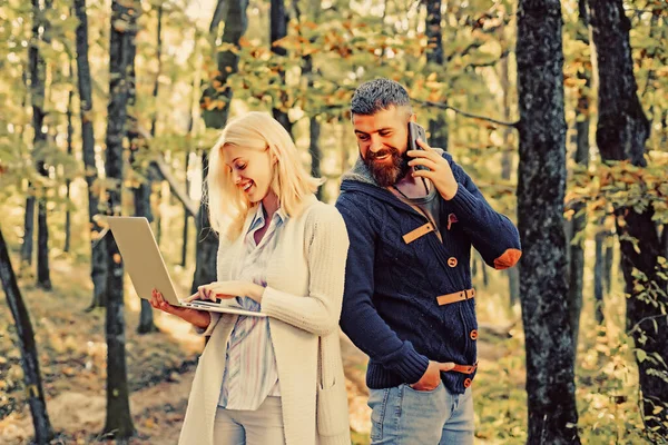 Κοινωνική έννοια των μέσων μαζικής ενημέρωσης. Επαγγελματικό ζευγάρι - άνδρας με κινητό τηλέφωνο, γυναίκα που χρησιμοποιεί σημειωματάριο σε εξωτερικούς χώρους. Επιχειρήσεις εξωτερική στο πάρκο φθινόπωρο. — Φωτογραφία Αρχείου