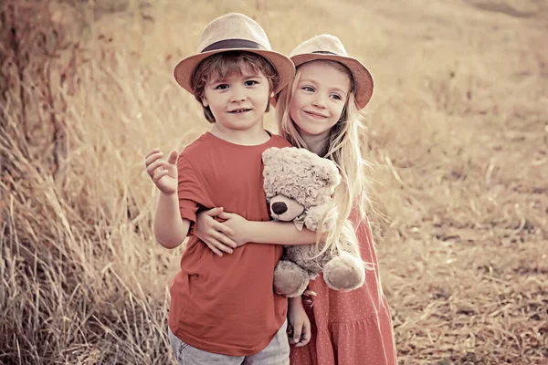 Kinder haben Spaß auf dem Feld vor dem Hintergrund der Natur. Glückliche Kinder umarmen sich im Sommer auf der Wiese in der Natur. Schöne Kinder. Valentinstag-Karte. — Stockfoto