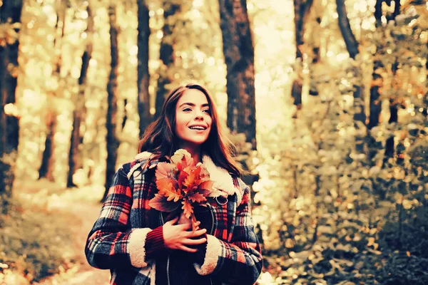 公園で明るい赤黄色の葉を持つ美しい若い幸せな女の子。暖かい晴天。ゴージャスブルネットモデルの女の子はチュールの長いガウンと見事な夜のドレスを身に着けています。秋の森. — ストック写真