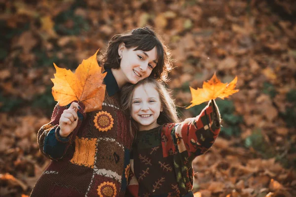 Zonnig herfstweer. Herfst concept. Laat de bladeren vallen in de handen van meisjes. Vrolijke lachende vrouw met zus die esdoornbladeren vasthoudt. Herfst stemming. Zusters genieten van het herfstweer. — Stockfoto