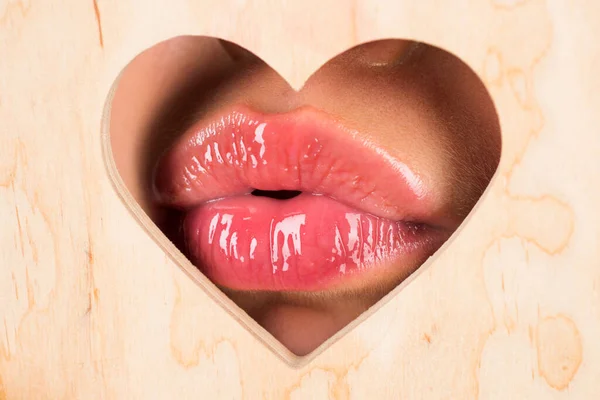 Χείλη σε σχήμα καρδιάς. Κόκκινο χείλος με γυαλιστερό lipgloss. Γλώσσα και σέξι. Κοντινό πλάνο, μακροεντολή με όμορφα στόματα. Σέξι φιλιά, αισθησιακά σαγηνευτικά χείλη μιας νεαρής γυναίκας. Καλλυντικά και σαλόνι ομορφιάς. — Φωτογραφία Αρχείου