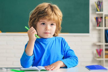 Okuldaki küçük çocuk. Çocuklar okula hazırlanıyor. Okul eğitimi ve insanların konsepti - karatahta üzerinde sevimli bir öğrenci.
