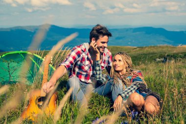 Çift kampı. Seyahat ve kamp yapan romantik bir çift. Genç turistler birlikte geziyorlar. Aşık bir çift ormanda turistik çadırın yanında oturuyor..