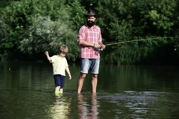Padre e hijo pescando. Pesca con mosca de trucha. Feliz padre e hijo pescando en el río sosteniendo cañas de pescar. Concepto de edad de jubilación . —  Fotos de Stock