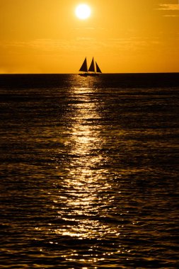 Gün batımında denizde bir tekne. Mavi yelkenli yelkenliler gün batımında.