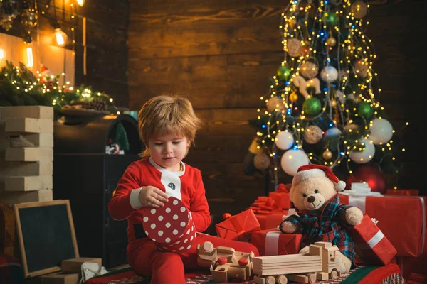 贈り物を開く。素敵な赤ちゃんはクリスマスをお楽しみください。家族の休日。男の子かわいい子供陽気な気分はクリスマスツリーの近くで再生します。メリーと明るいクリスマス。サンタ少年の子供お祝いクリスマスに家 — ストック写真