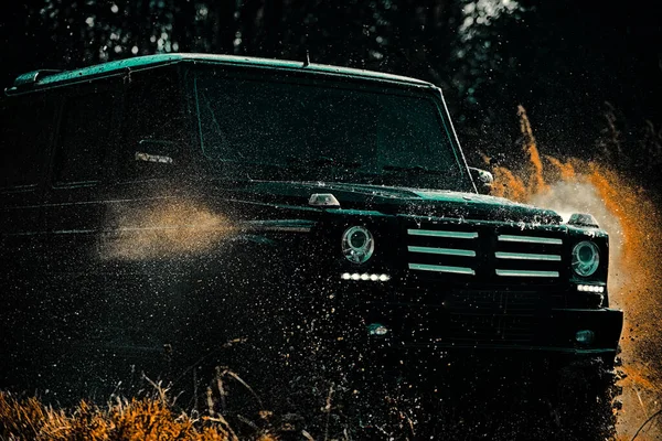 Färdas off-road på bergsväg. Offroad sport lastbil mellan bergen landskap. Offroad-fordon som kommer ut ur en lerhålsfara. Mudding är off-roading genom ett område av våt lera eller lera. — Stockfoto