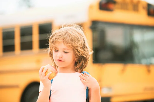 Школьник в школьном автобусе. Ученик с яблоком. — стоковое фото